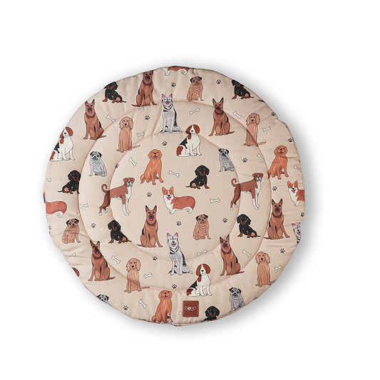 Top view of the Dog Daze round pet mat with a beige base, featuring an all-over cartoon dog print with multiple breeds, paw prints, and bone motifs for cozy pet lounging.