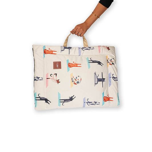 Folded yoga mat with colorful animal print design, shown being carried by hand using an attached handle, highlighting its lightweight and travel-friendly portability.