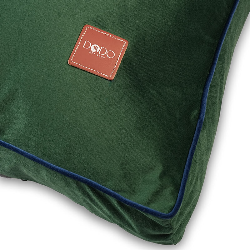 Close-up view of Luna Lounge Bed showing DODO Pet Care brand logo on green velvet fabric with blue piping detail