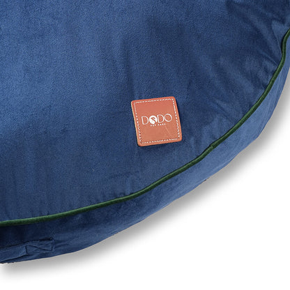 Close-up of Luna Round Bed showing DODO Pet Care brand logo on soft blue velvet fabric with green piping detail