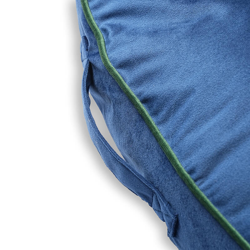 Side view of Luna Round Bed showing built-in fabric handle, blue velvet material, and green piping for easy movement