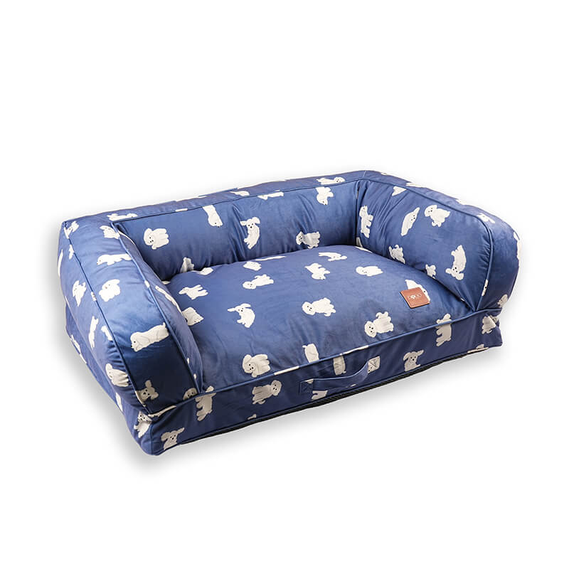 Angled view of the blue Luxe Lounge Sofa Bed for dogs with plush cushioned sides, soft velvety fabric featuring white dog prints, supportive base, and DODO Pet Care logo, isolated on a white background.