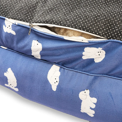 Close-up of the Luxe Lounge Sofa Bed showing the concealed zipper and removable cover design, featuring blue velvety fabric with white dog prints, inner cushioning visible, and a non-slip dotted base on a white background.