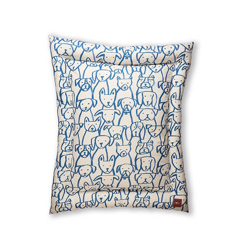 Front view of the Paw Pop Bed featuring a playful blue hand-drawn dog illustration pattern on a cream base, with soft padding and raised edges designed for cozy and supportive rest for dogs and cats.