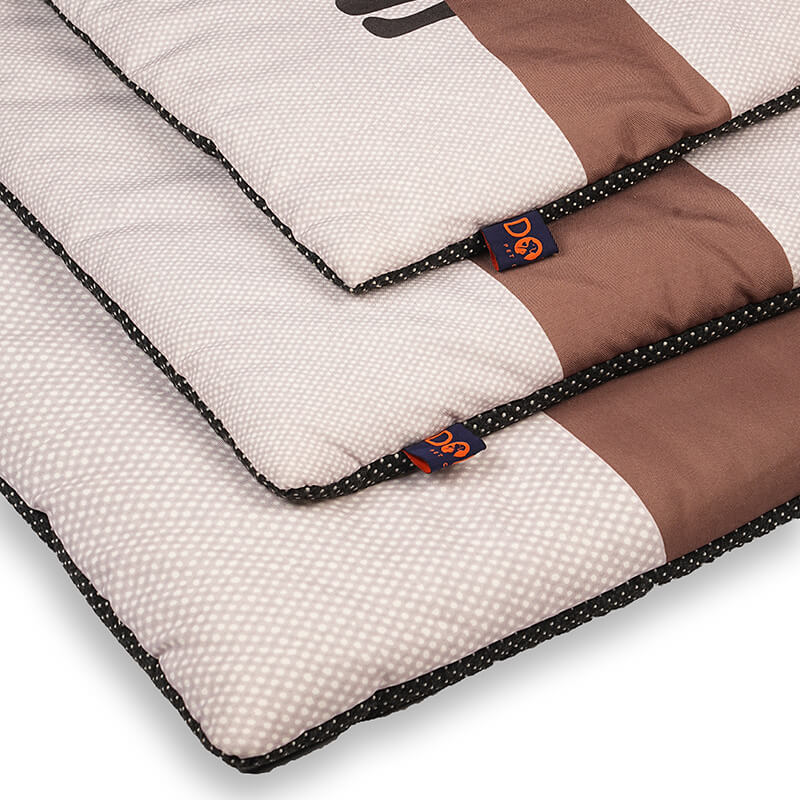 Close-up of Sniffy travel mat showing quilted padding, soft fabric surface, and branded tag, highlighting comfortable cushioning and durable stitching for pets on the go
