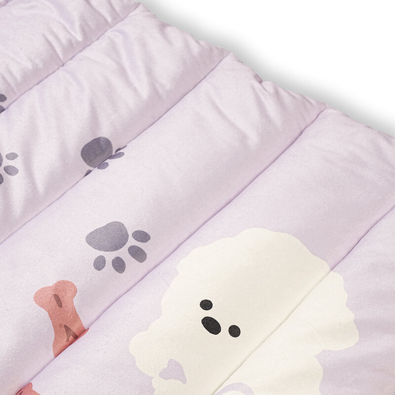 Close-up of Treatos travel mat showing soft quilted padding with pastel pink fabric, paw prints, bone pattern, and a cute dog illustration for comfortable pet resting.