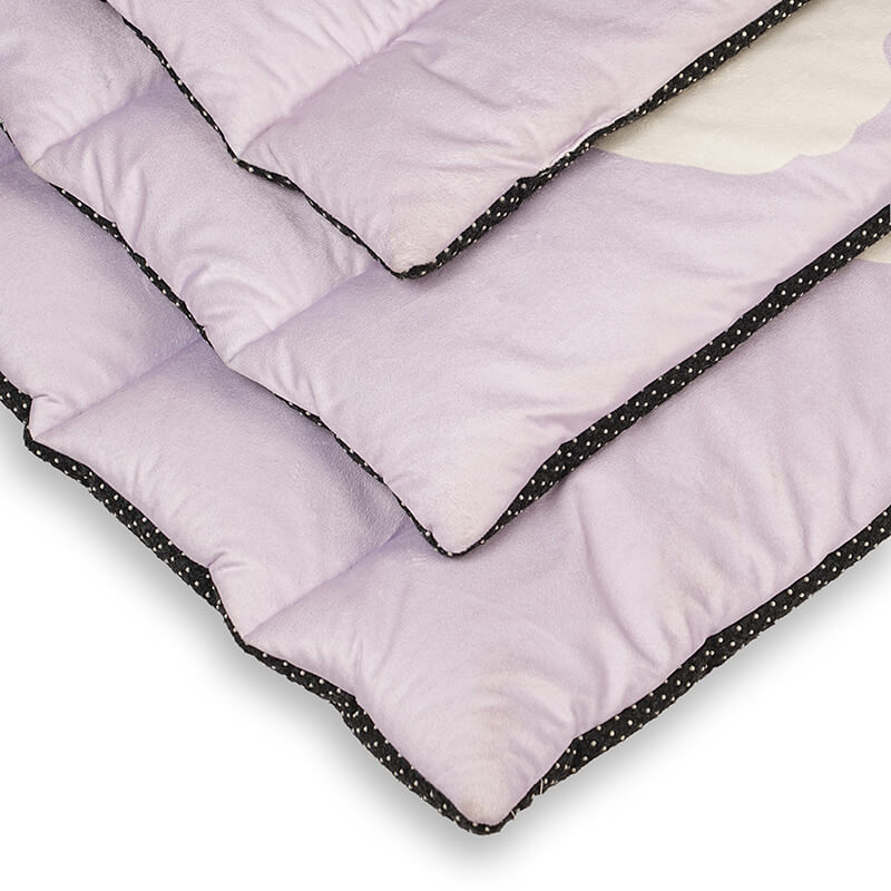 Close-up view of the Treatos Travel Mat showing soft quilted padding with layered edges, lavender fabric surface, and black anti-slip dotted border designed for comfortable pet rest and travel use.
