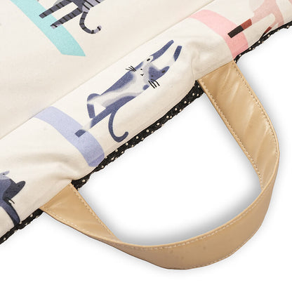 Close-up of a foldable yoga mat showing the stitched carry handle, printed fabric surface, and dotted anti-slip backing along the edge for secure grip and easy transport