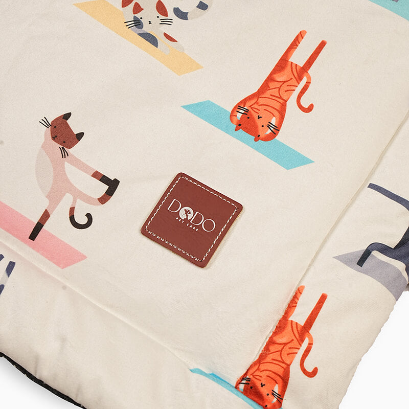 Close-up of a foldable yoga mat featuring a stitched brand patch on soft premium fabric with playful animal prints, highlighting quality stitching, comfort, and design detail.
